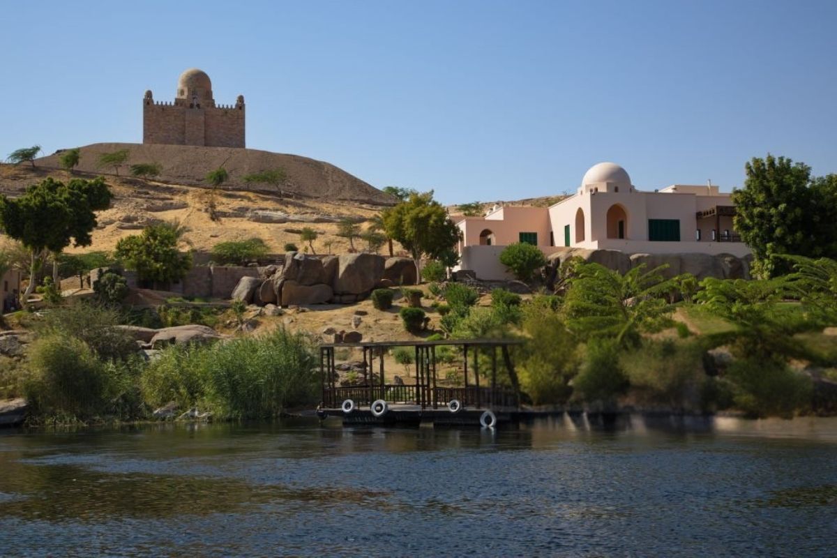 A colorful Nubian guesthouse in Aswan with traditional architecture and vibrant painted walls surrounded by a serene desert landscape